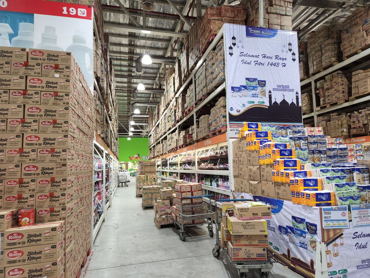 High shelves in a warehouse stocked with a variety of merchandise and large cardboard boxes.